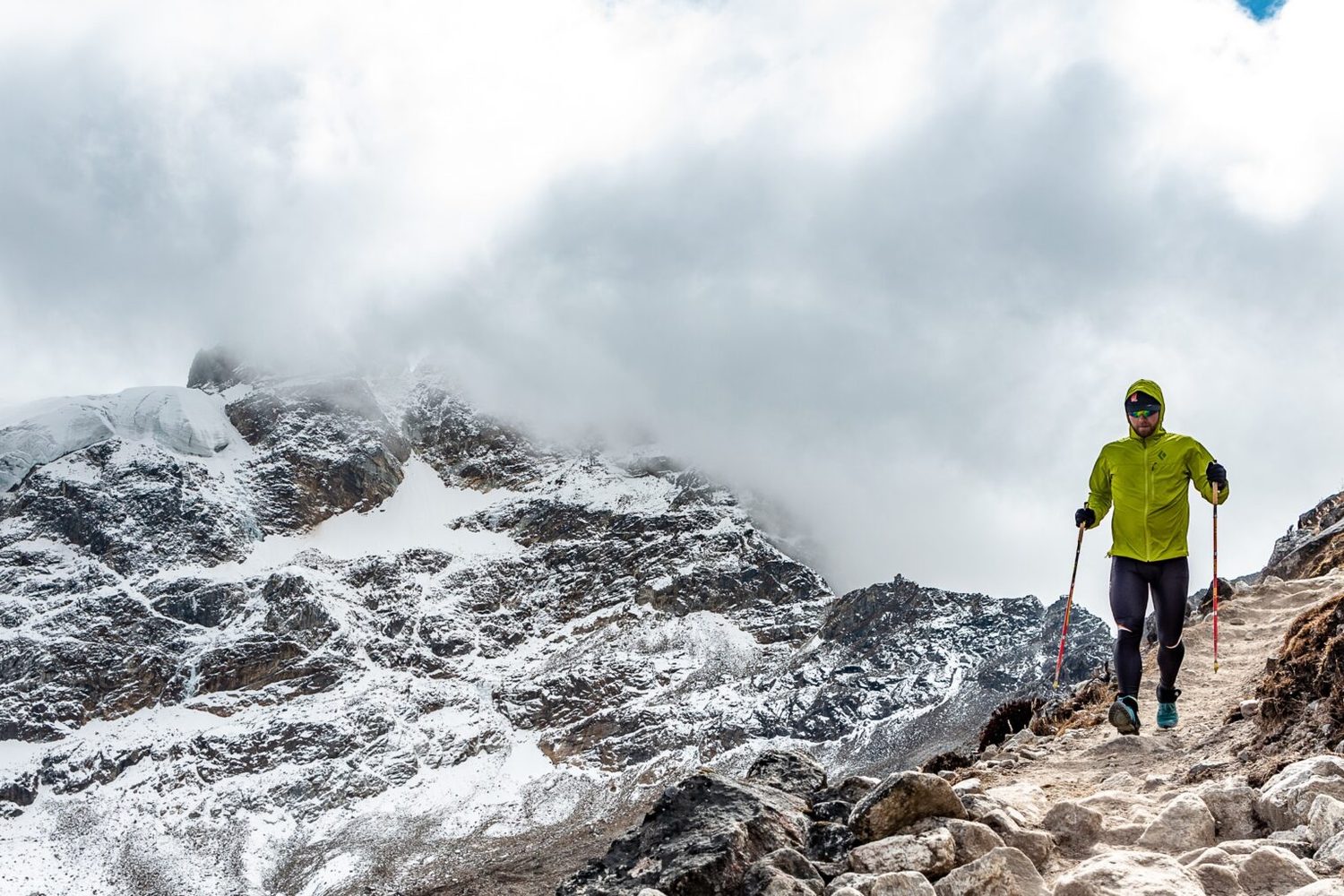 A trail runner on a stone path below snow-covered peaks in northern Bhutan