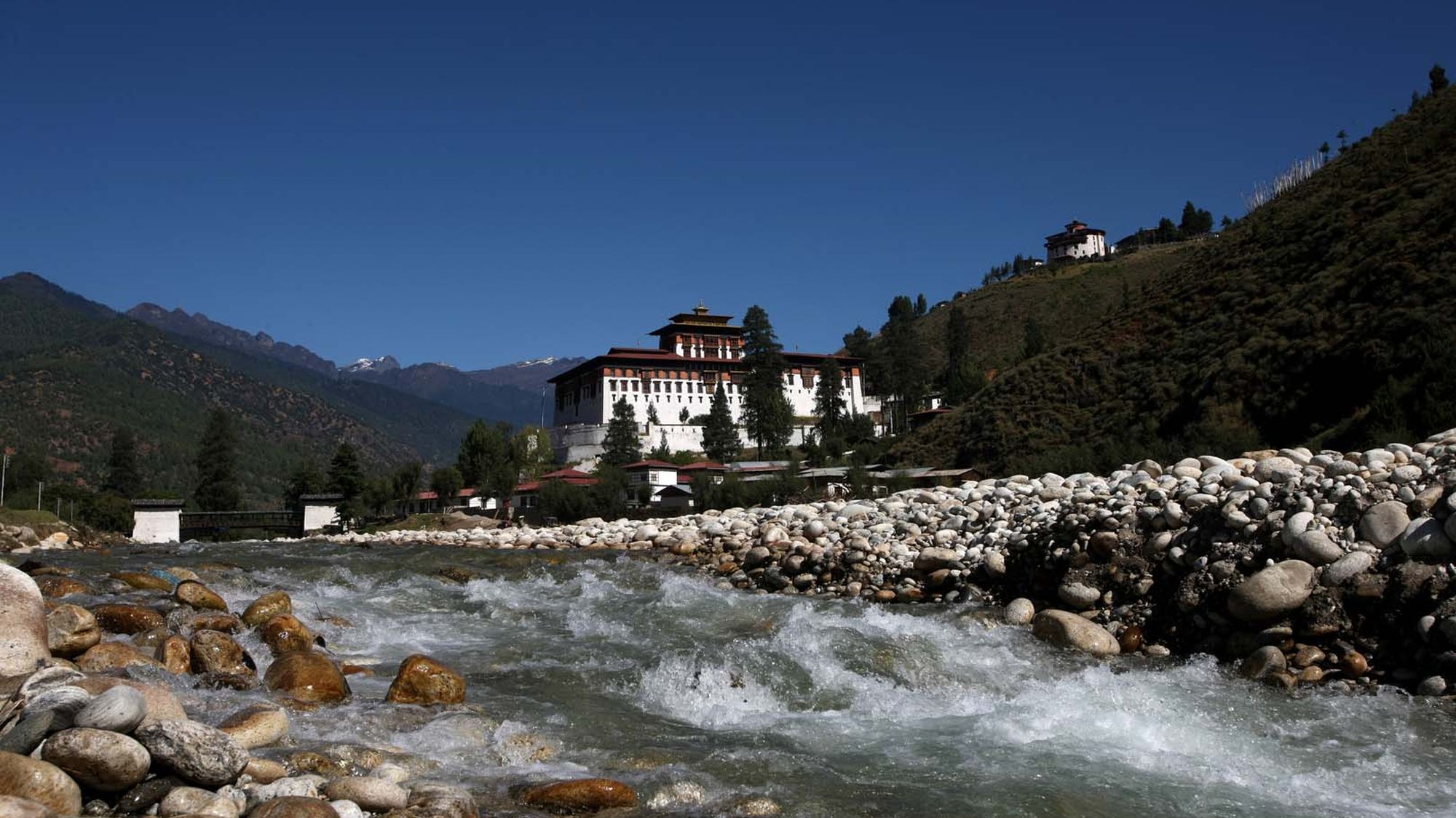 Rinpung Dzong above the fast water of the Paro Chhu, with mountains behind